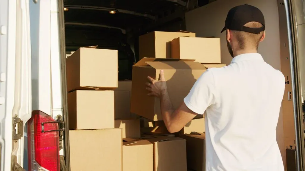 Man loading cardboard boxes into the back of a van