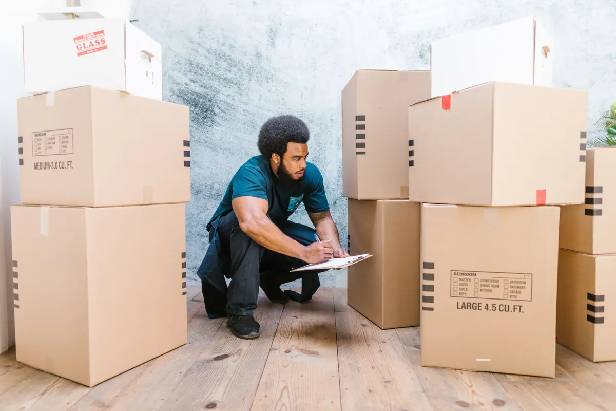 Man taking notes on a clipboard among moving boxes